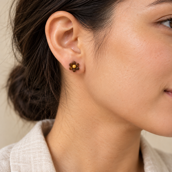 Brown daisy flower stud earring with six petals, worn by an adult woman