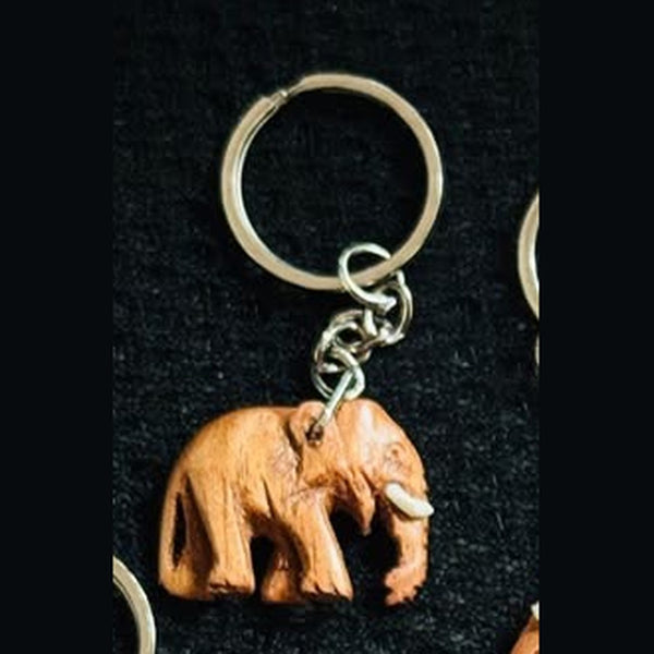 Close-up of carved wooden elephant keychain with silver key ring
