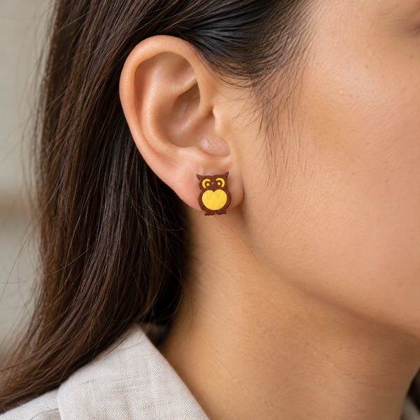 Midnight owl stud earrings with a flat face, worn by an adult woman