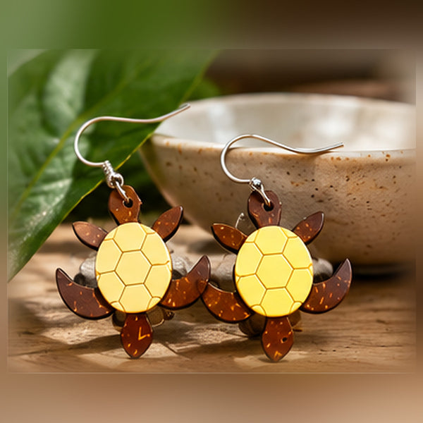 Pair of yellow and brown sea turtle earrings styled with ceramic bowl and leaves