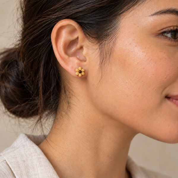 Yellow daisy flower stud earring with six petals, worn by an adult woman